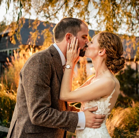 Bride and groom kissing at golden hour at Kimbridge Barn, Hampshire