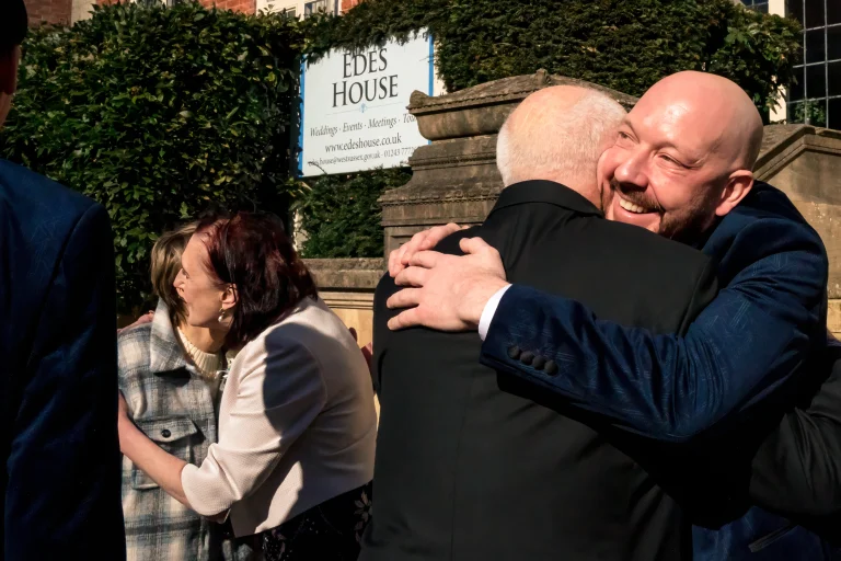 Two grooms sharing a hug at Edes House, Chichester
