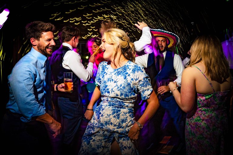Guests dancing on a packed wedding dancefloor lit with flash