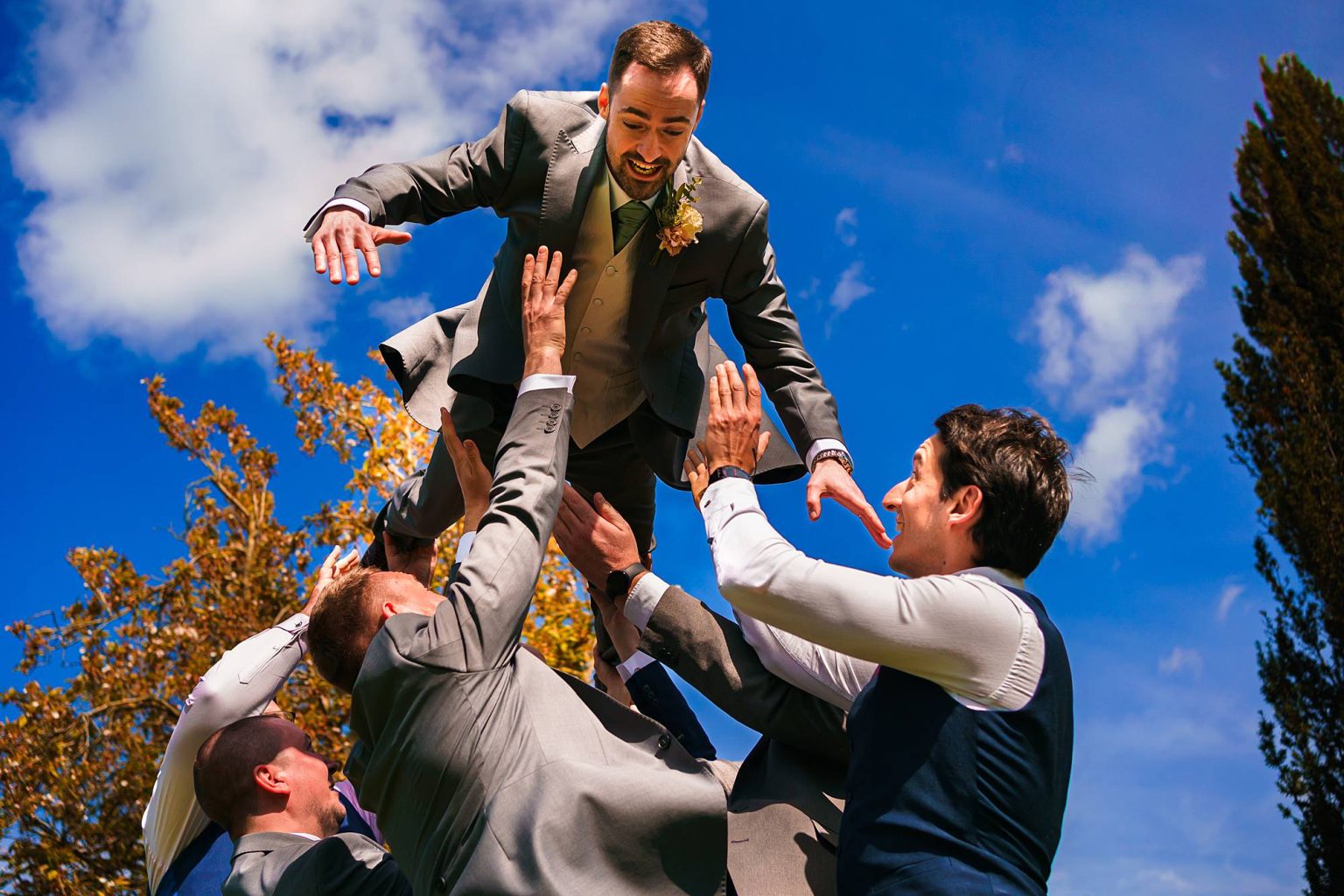 Groomsmen throwing the groom in the air