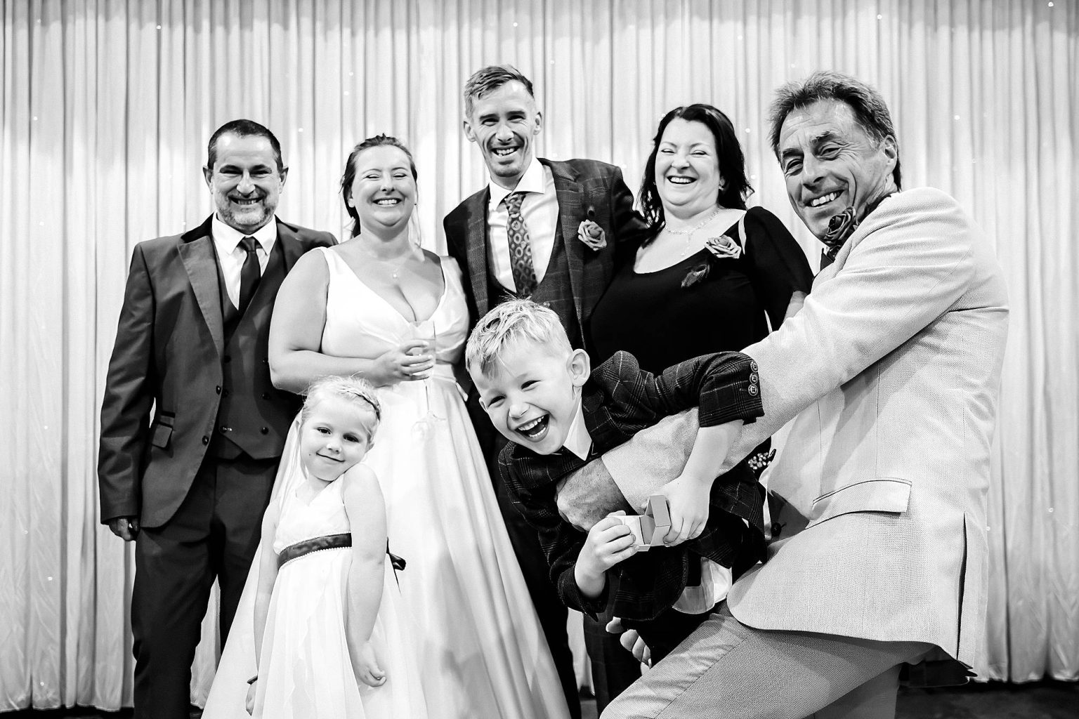 Fun family formal with everyone pulling silly faces, black and white