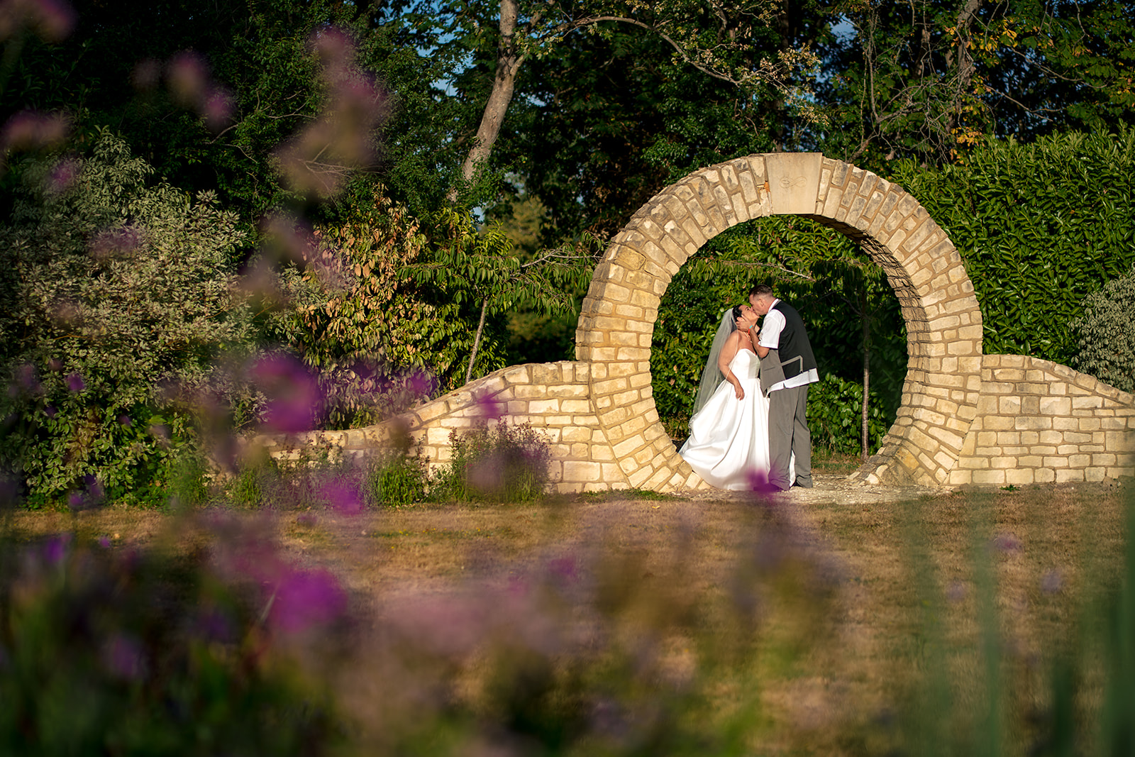 Bride and groom portrait by the stone moon gate at Farnham House Hotel, Surrey