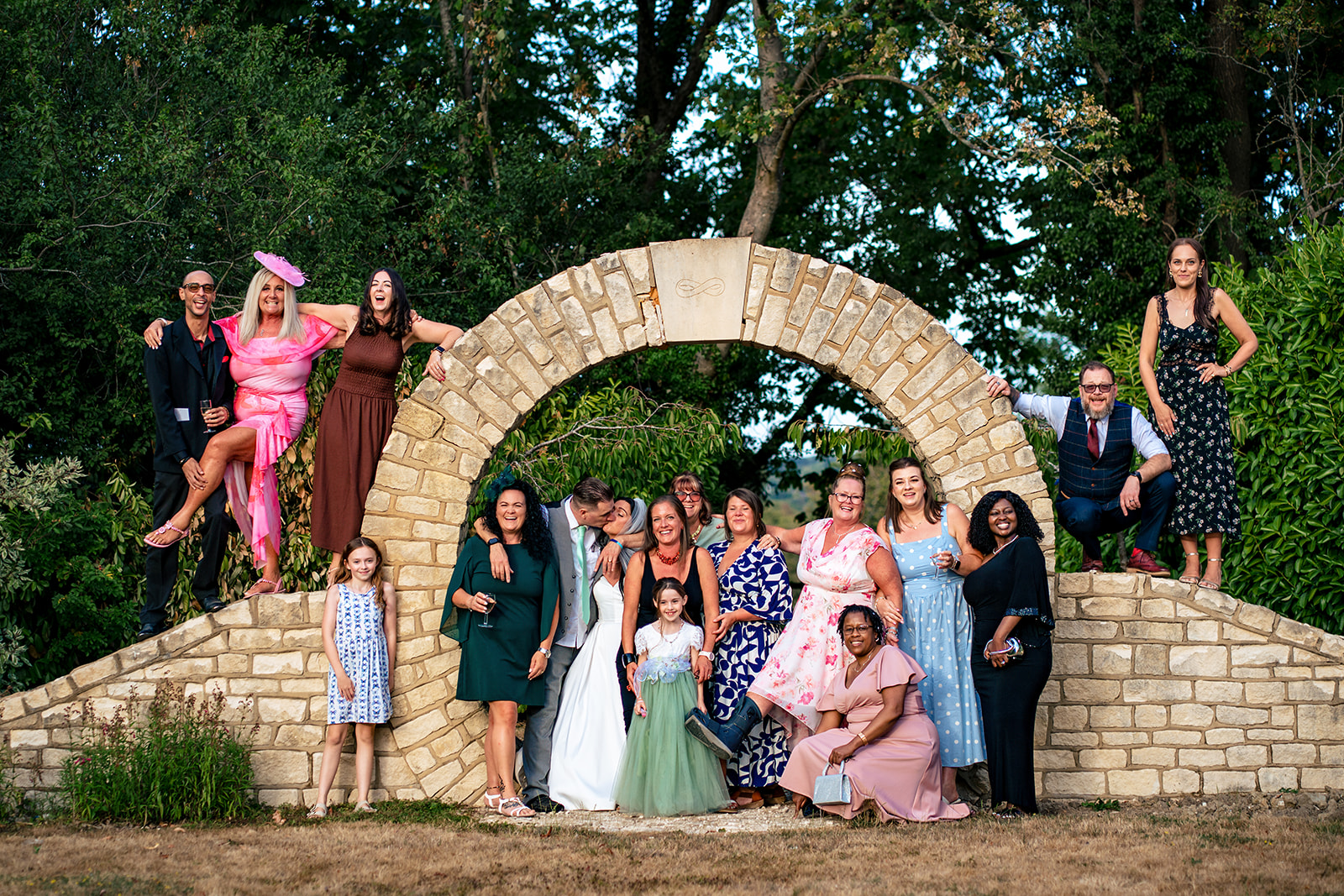 Bridal party group photo by the stone moon gate at Farnham House Hotel, Surrey