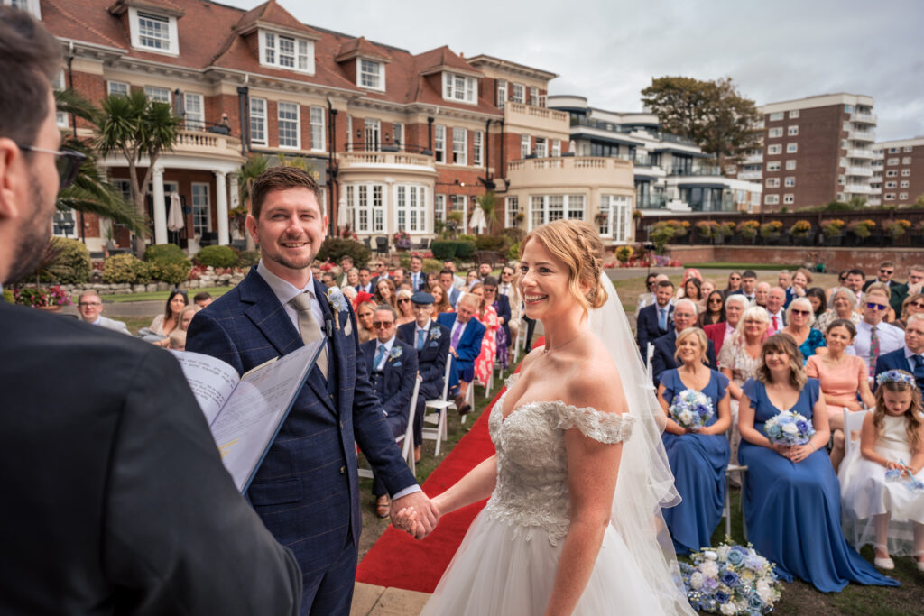 Bride and groom smiling at their guests during the outdoor ceremony at Hotel Miramar
