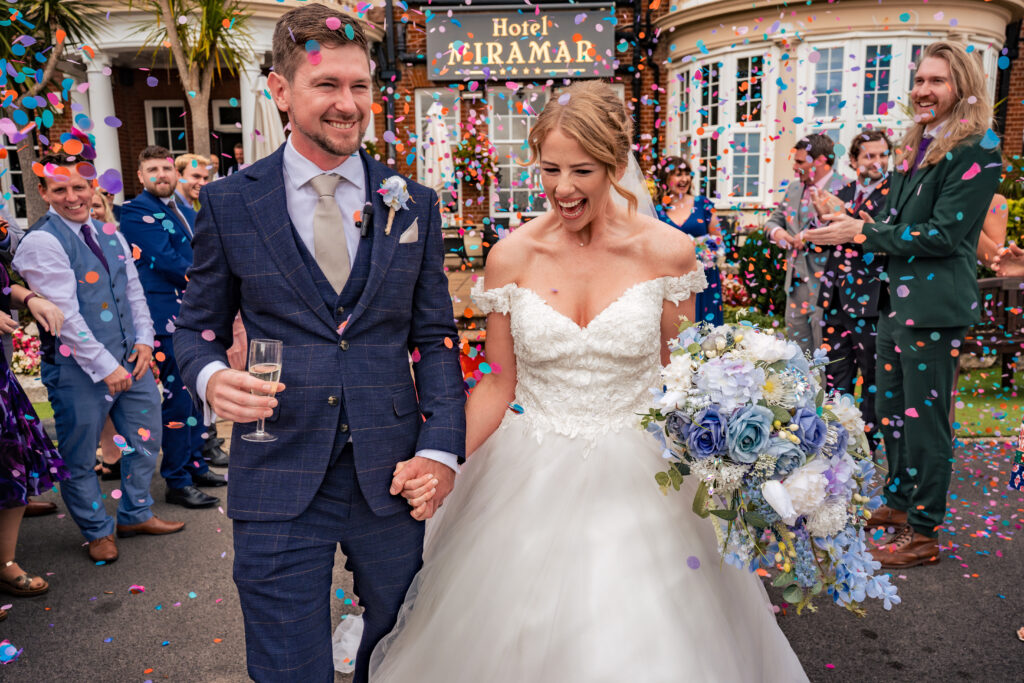 Bride and groom walking through confetti in front of Hotel Miramar Bournemouth