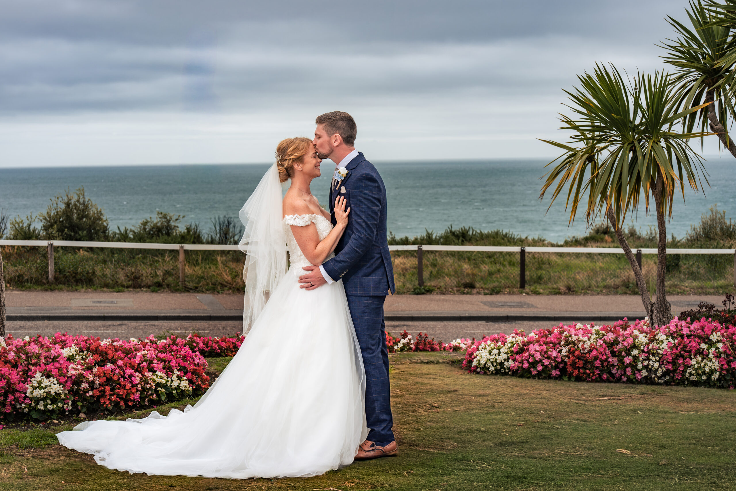 Bride and groom kissing on the clifftop gardens overlooking the sea at Hotel Miramar