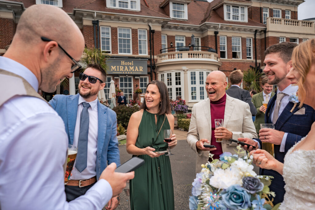 Guests laughing together with drinks on the lawn at Hotel Miramar Bournemouth