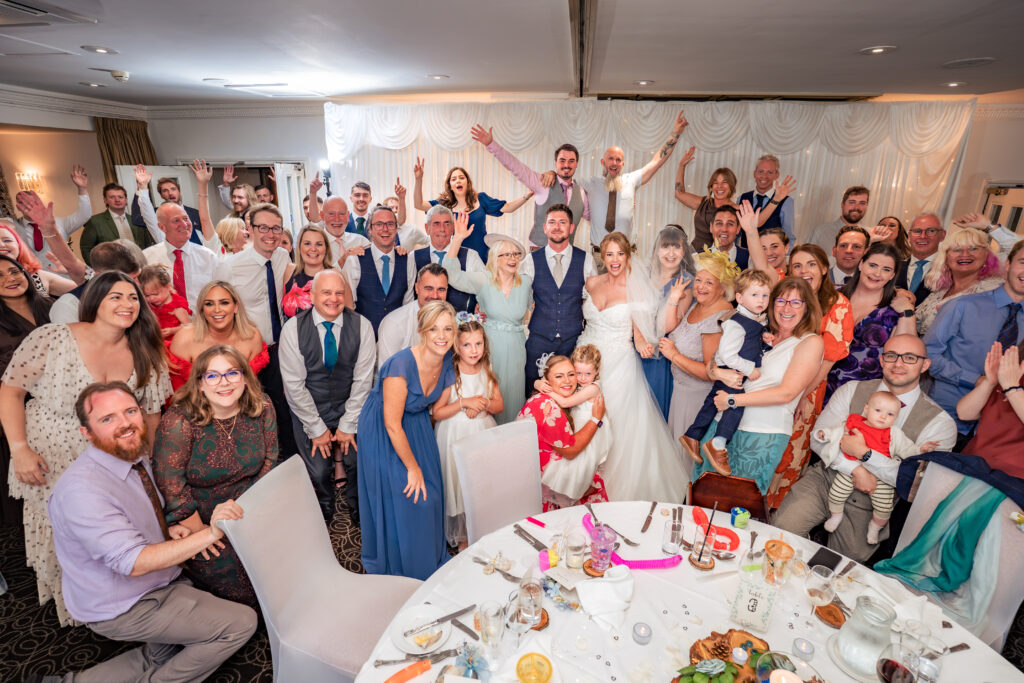 Whole room of wedding guests cheering with arms in the air at Hotel Miramar Bournemouth