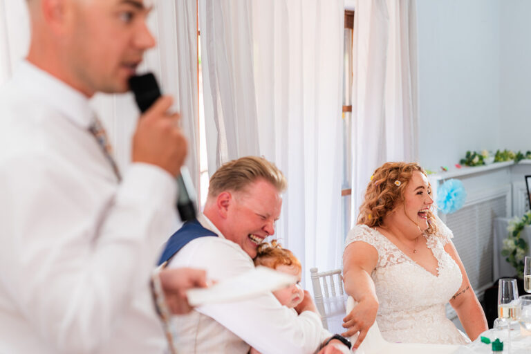 Bride and groom crying with laughter during the wedding speeches