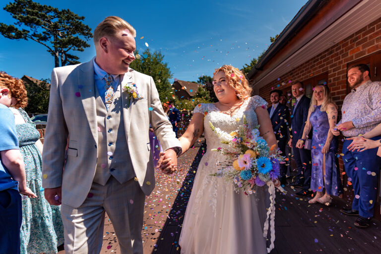 Bride and groom walk through a shower of confetti at Newtown House Hotel, Hayling Island