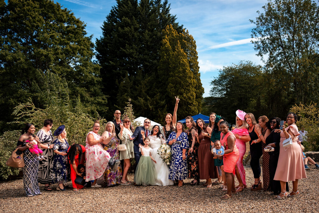 Wedding guests celebrating in the gardens at Farnham House Hotel, Surrey