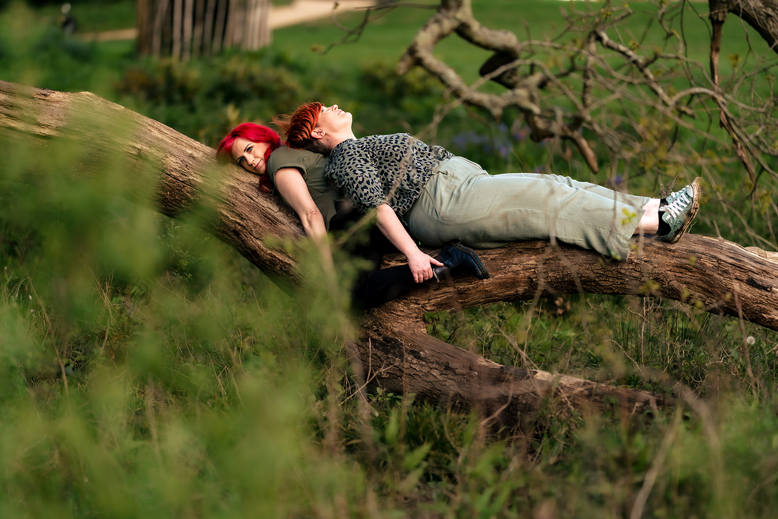 Couple draped over a fallen log at their 80s themed engagement shoot