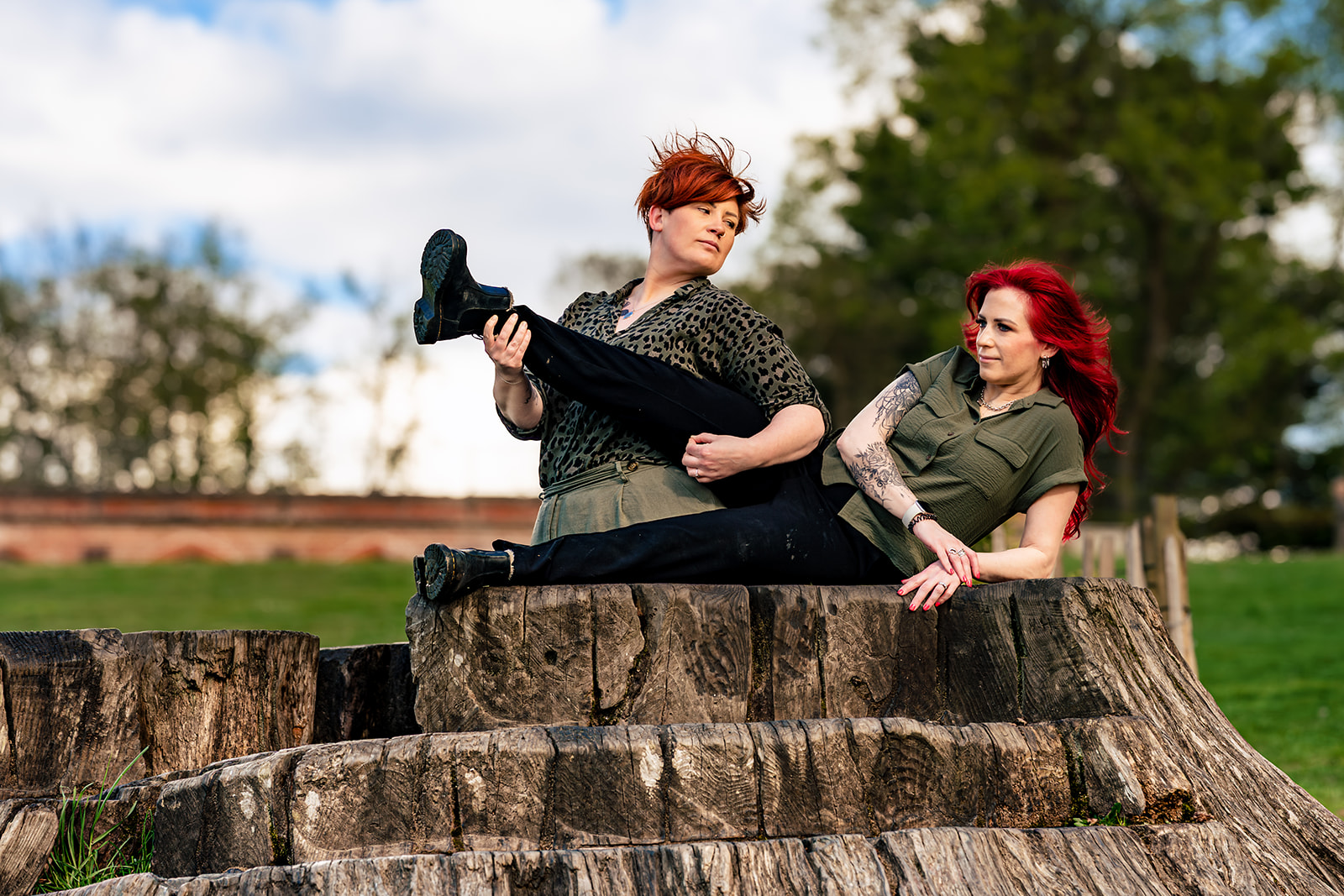 Playful leg-kick pose on a tree stump at an 80s themed engagement shoot