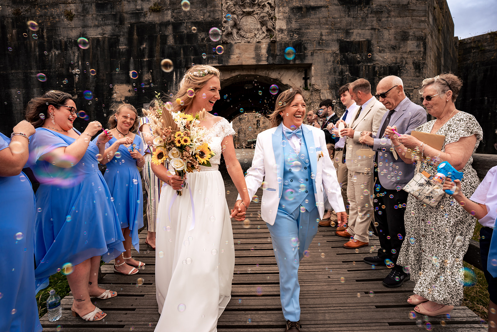 Two brides walking down the steps at Southsea Castle through a confetti throw