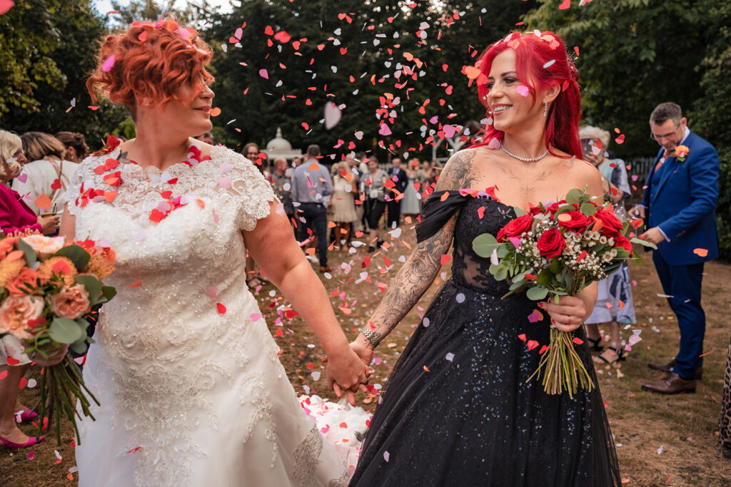 Two brides walk through colourful confetti at The Elephant at Pangbourne, Berkshire