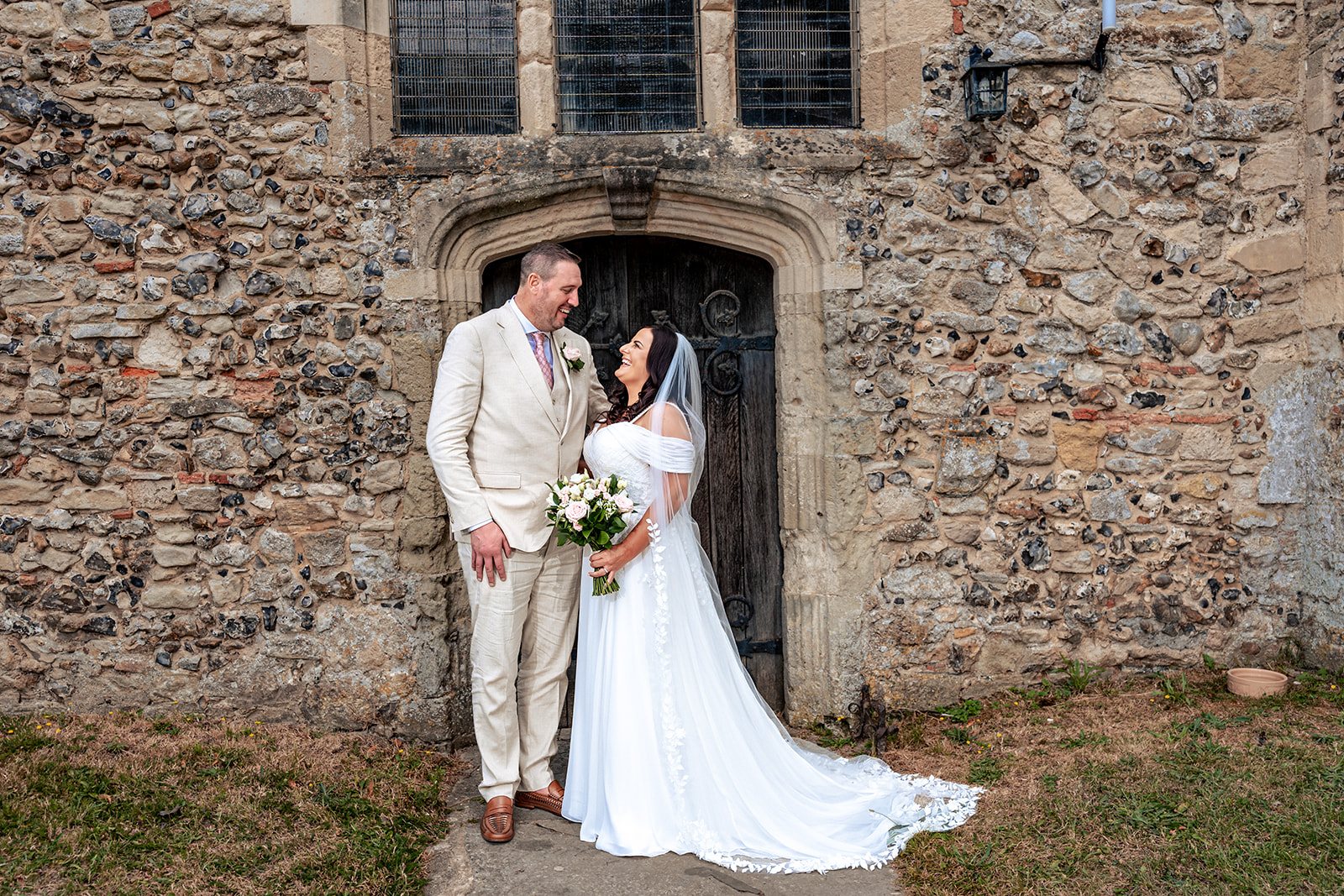 Bride and groom recreating their parents’ wedding photo in the doorway of St Thomas à Becket Church, Warblington
