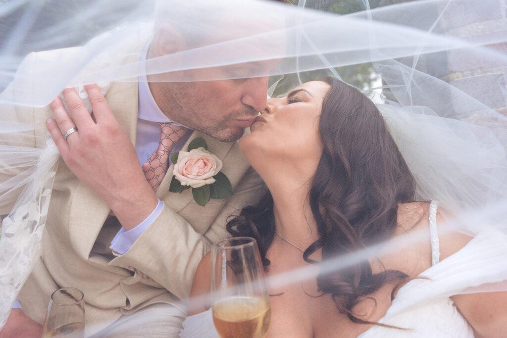 Bride and groom share a kiss under the veil at their Hampshire micro wedding