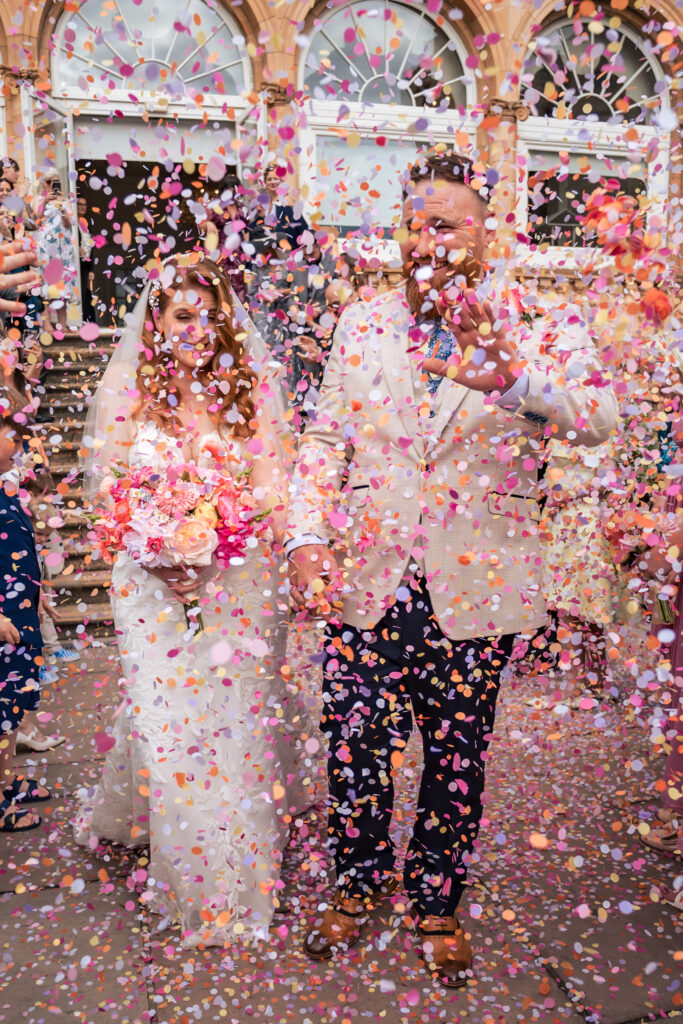Bride and groom walking through a colourful confetti blizzard at The Queens Hotel Southsea