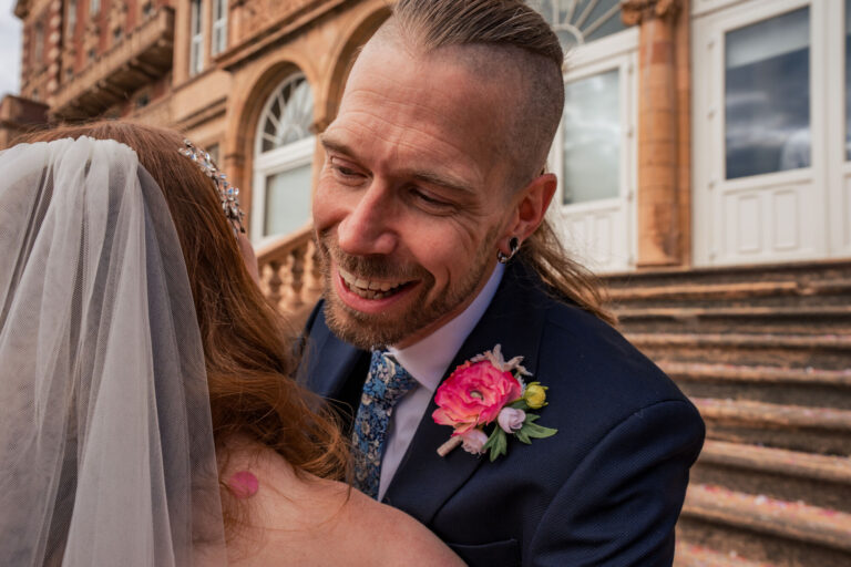Bride and groom sharing a hug outside The Queens Hotel