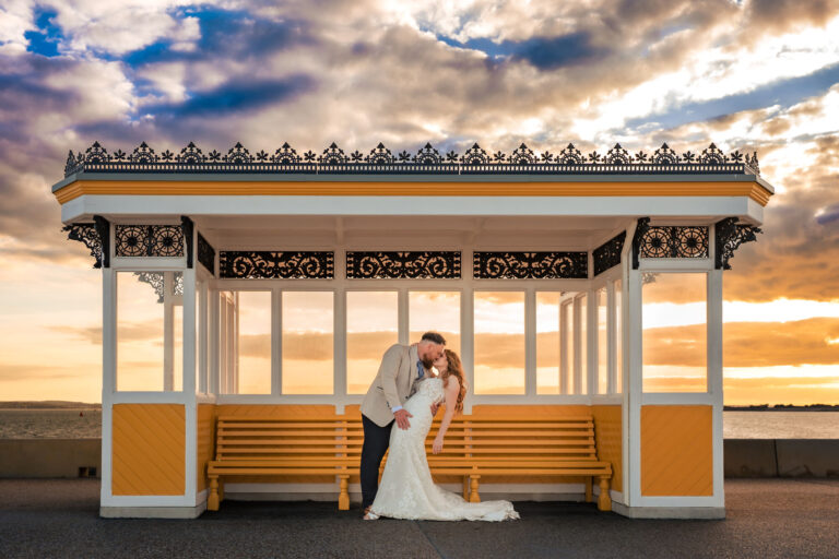 Bride and groom kissing in a seafront shelter at sunset near The Queens Hotel Southsea