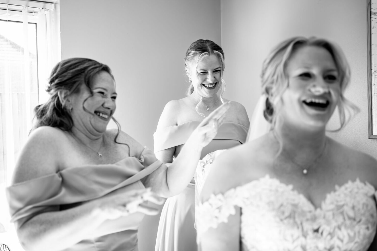 Bridesmaids and bride laughing together during bridal prep, black and white
