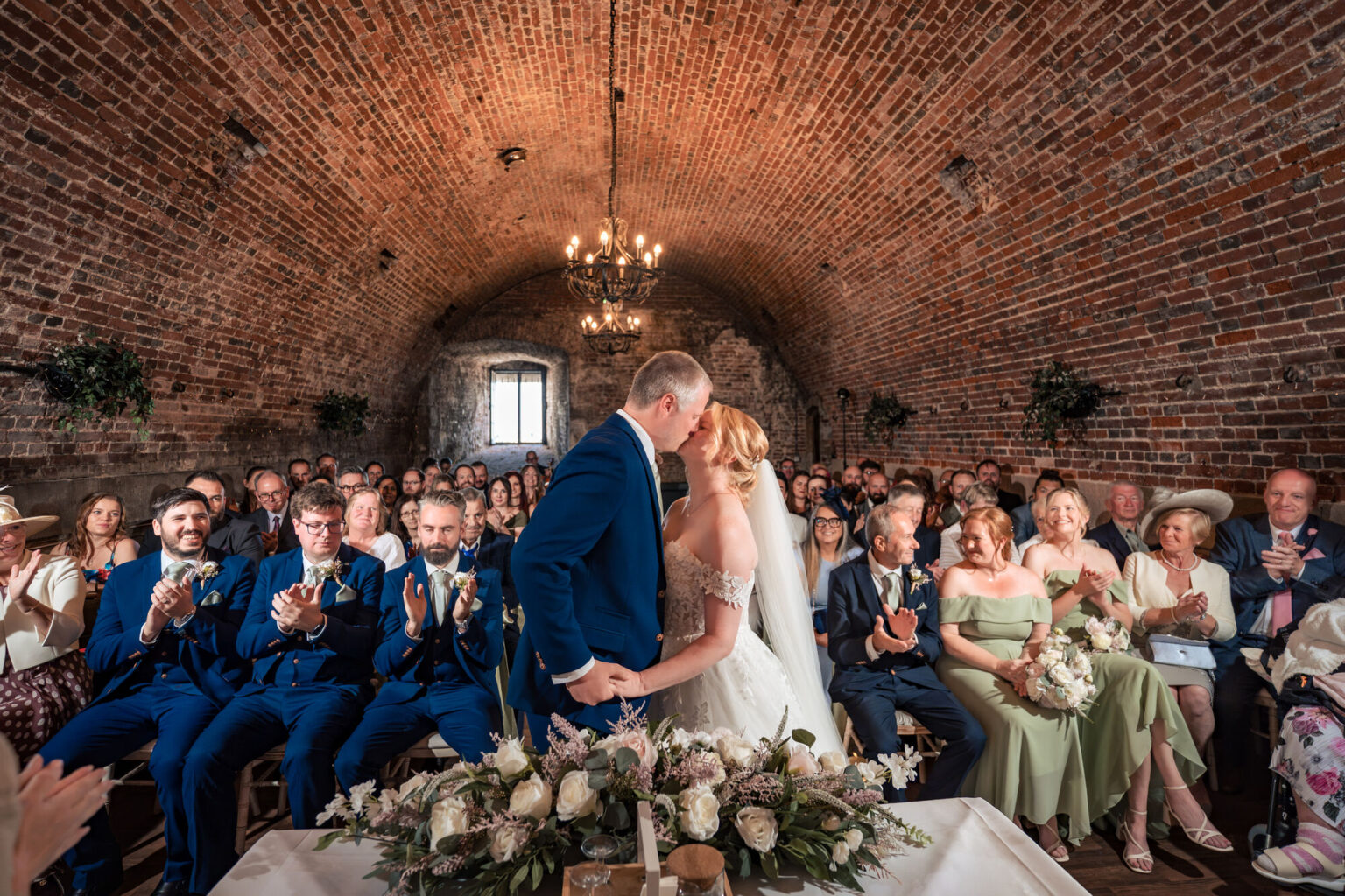 First kiss lit with off camera flash in the vaulted brick ceremony room at The Square Tower