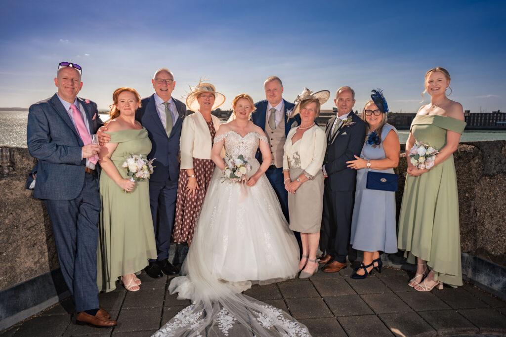 Full wedding party group photo on the rooftop of The Square Tower with Portsmouth Harbour behind