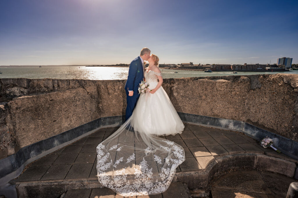 Bride and groom kissing on the rooftop of The Square Tower with the veil spread out and harbour views
