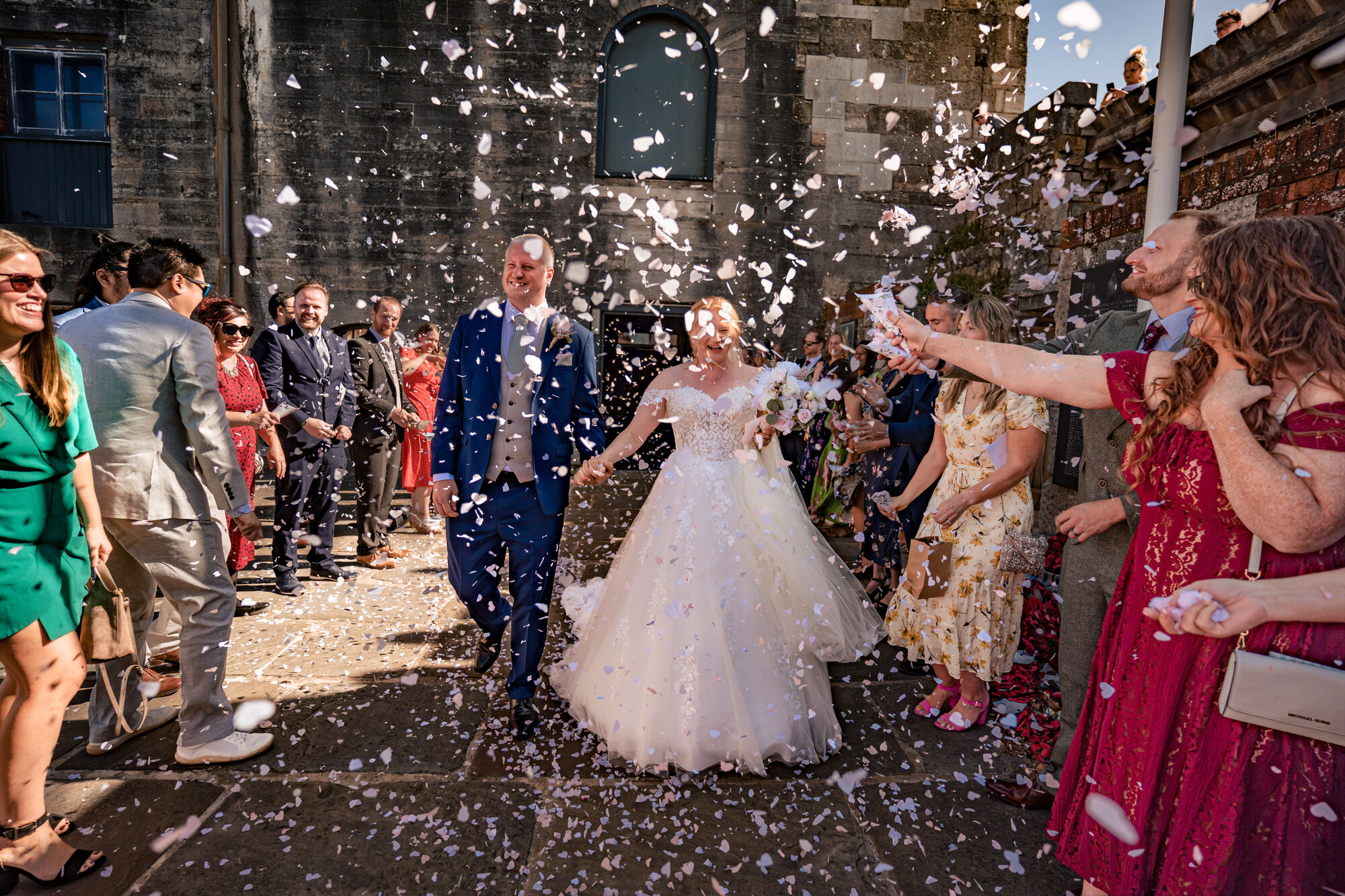 Bride and groom walking through a huge confetti throw outside The Square Tower Old Portsmouth