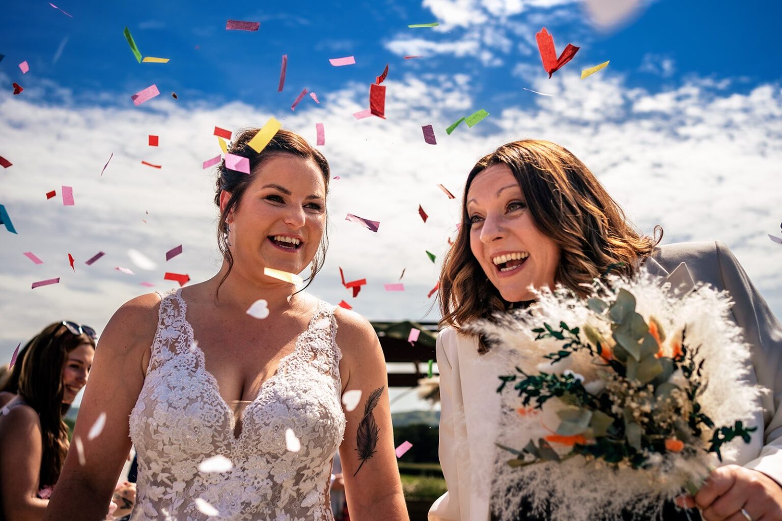 Two brides laughing under a confetti throw at Southlands Barn