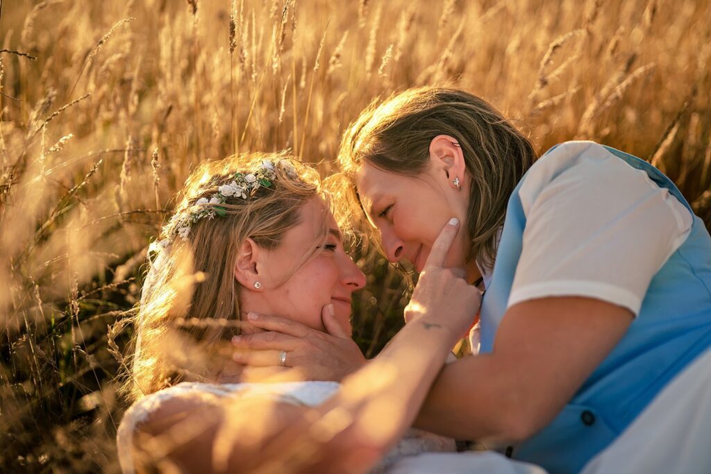 Two brides sharing a moment in golden wheat at sunset near Southsea Castle