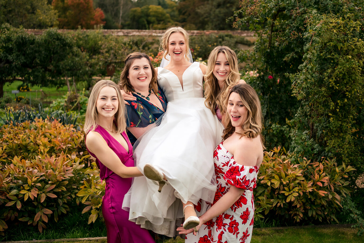 Bridesmaids lifting the bride in the gardens at Houghton Lodge Gardens