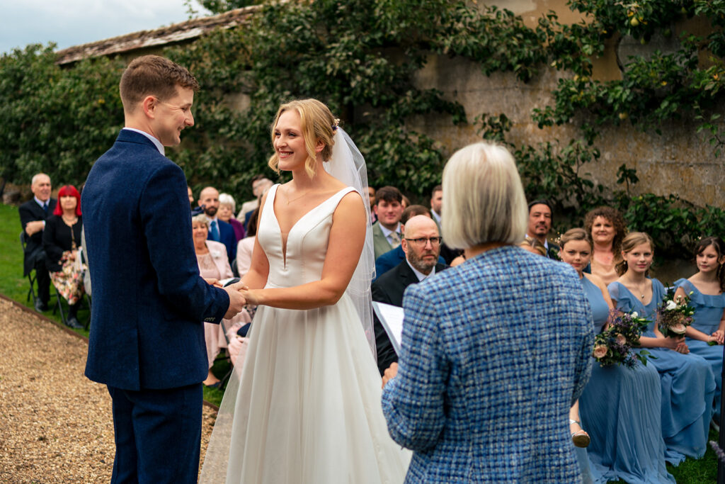 Bride and groom holding hands during their outdoor ceremony at Houghton Lodge Gardens