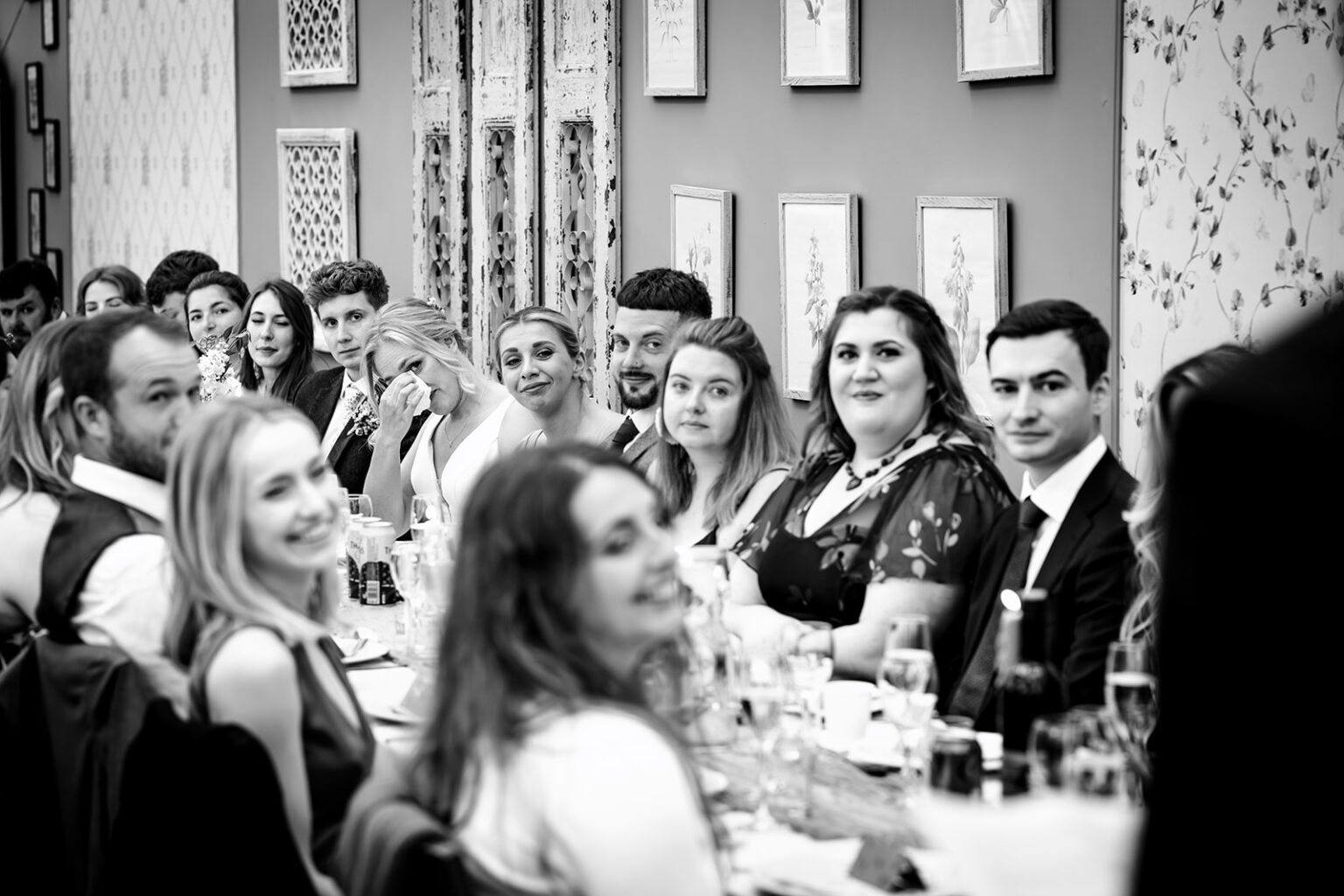 Bride, groom and guests laughing during the speeches at Houghton Lodge Gardens, black and white