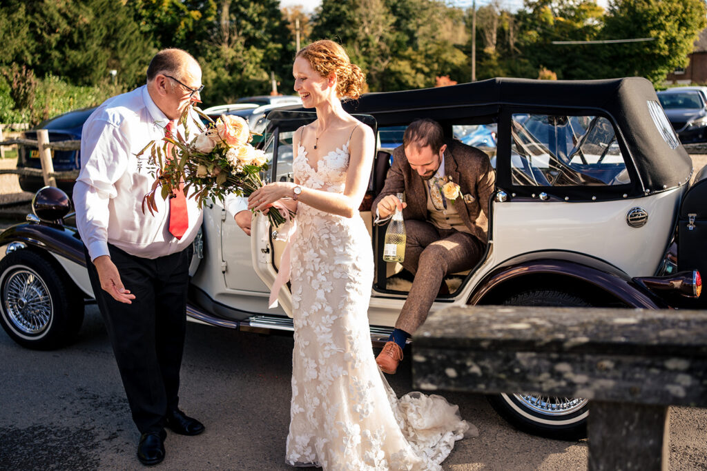 Bride and groom arriving by vintage car at Kimbridge Barn, Test Valley, Hampshire