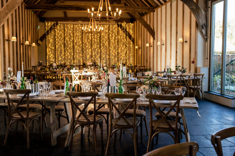The barn dressed for the wedding breakfast with festoon lights at Kimbridge Barn, Test Valley, Hampshire