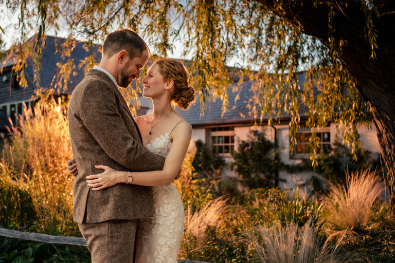 Bride and groom kissing under a tree in a flash-lit fake sunset at Kimbridge Barn, Test Valley, Hampshire