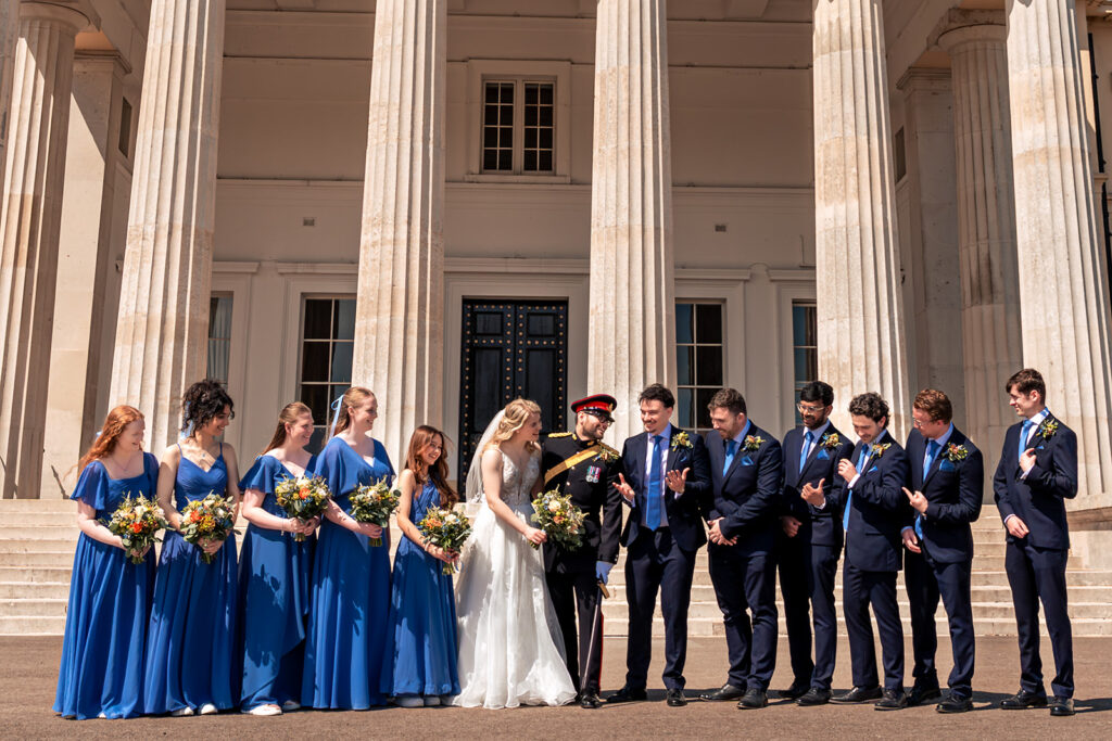 Bride and groom with their wedding party between the columns at the Royal Military Academy Sandhurst