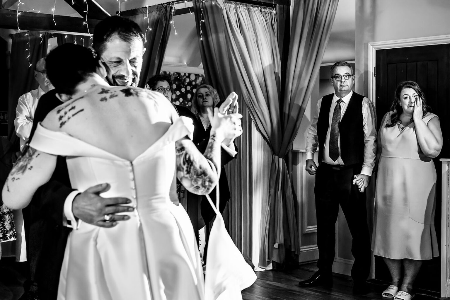 Mum wiping away a happy tear on the sidelines as her daughter dances with her dad