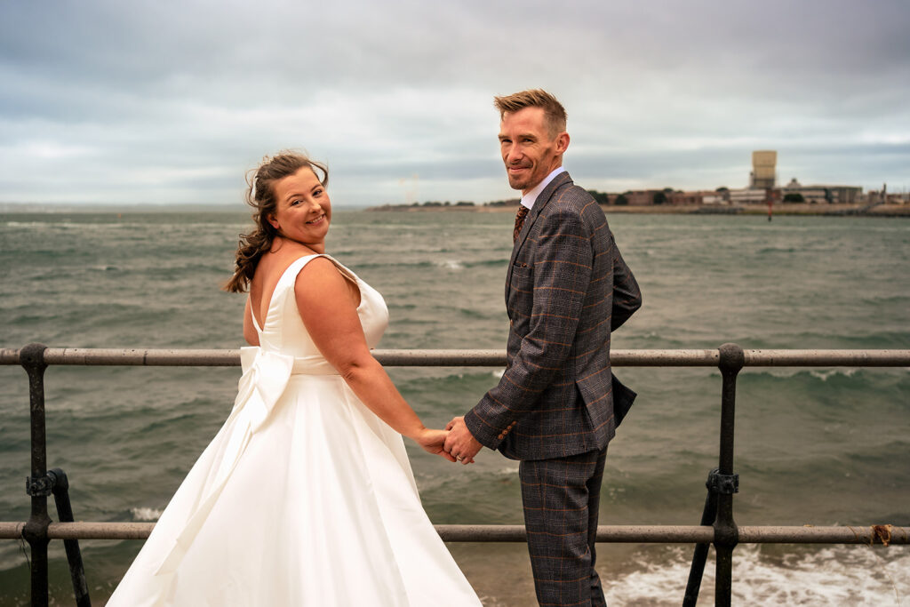 Bride and groom by the sea railings at The Square Tower, Old Portsmouth