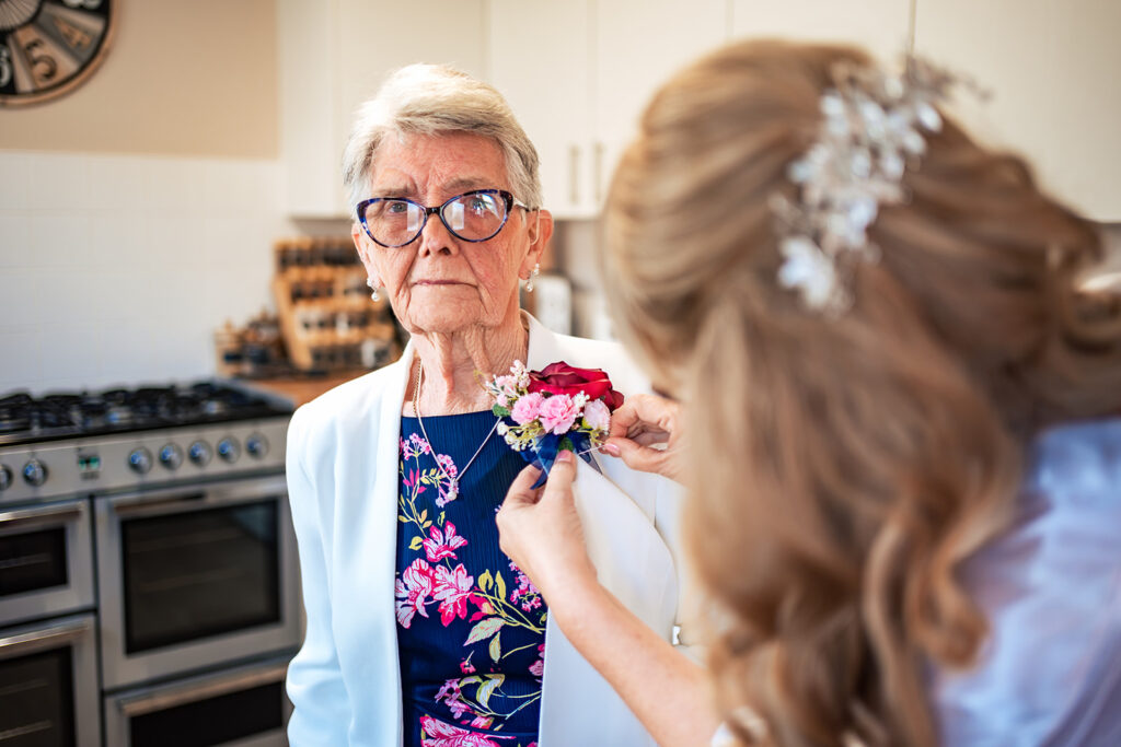 Bride pinning a buttonhole on her mum on the morning of a Portsmouth wedding