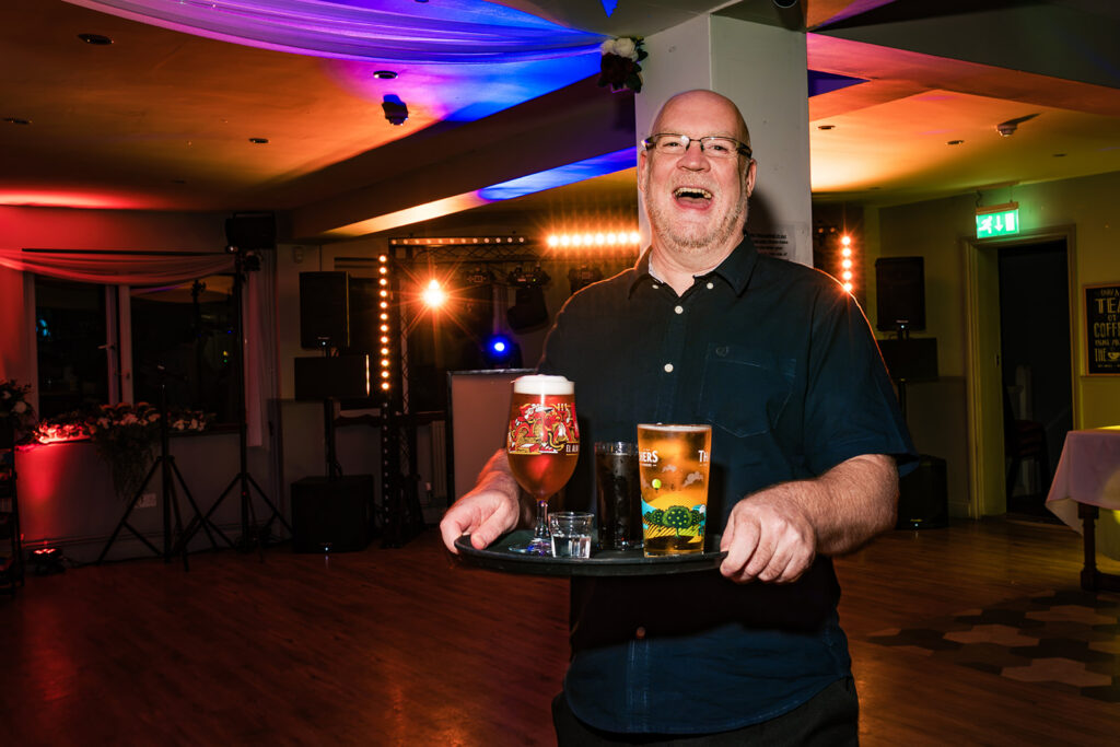 Guest carrying drinks across the dancefloor at The Churchillian, Portsdown Hill, Portsmouth