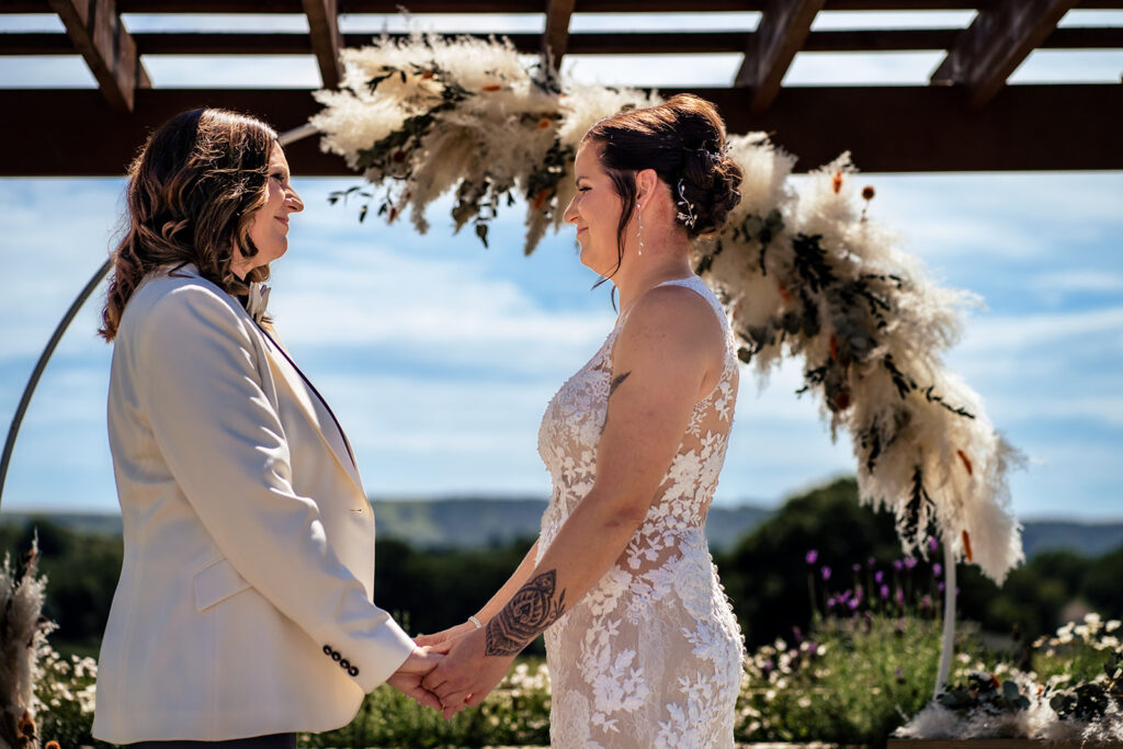 Two brides exchanging vows under the arbour at Southlands Barn, West Sussex
