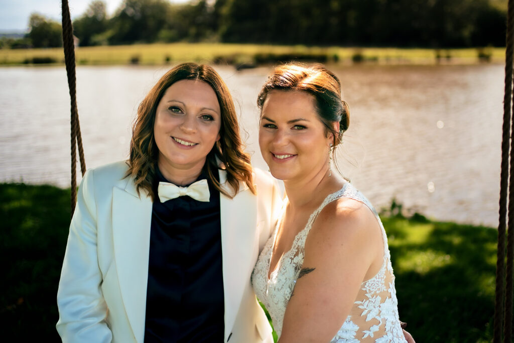 Two brides portrait by the lake at Southlands Barn, West Sussex