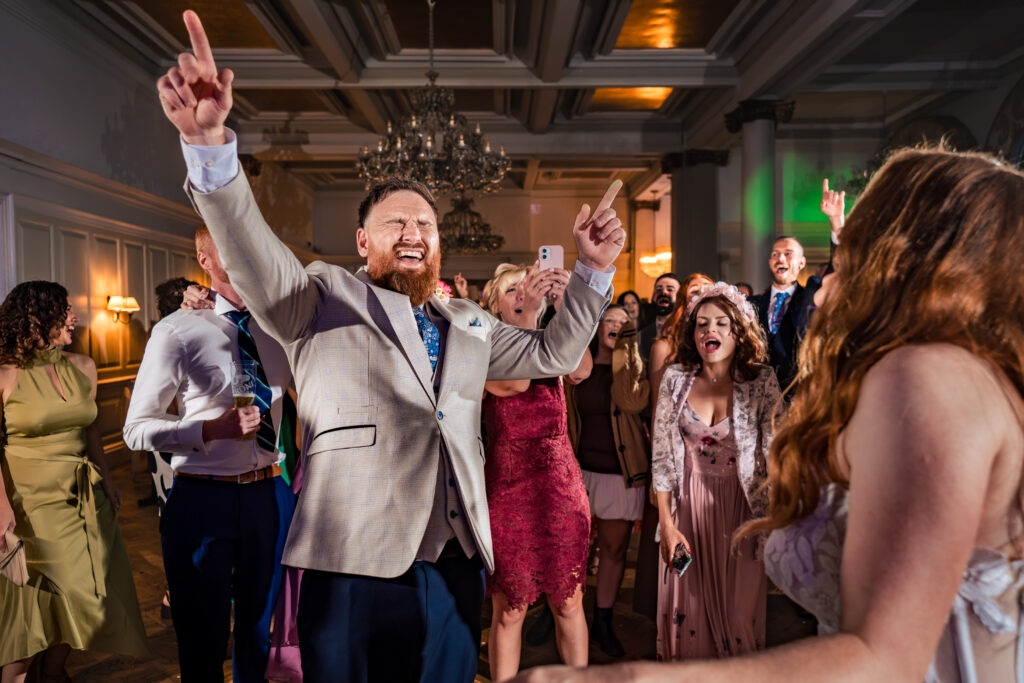 Groom pointing to the ceiling on the dancefloor at The Queens Hotel Southsea