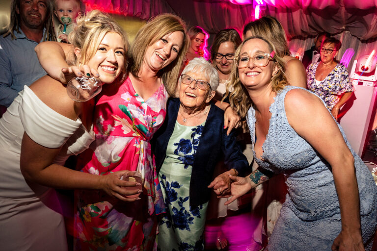 Nanna dancing with the bride and guests under pink lights at Tournerbury Woods Estate