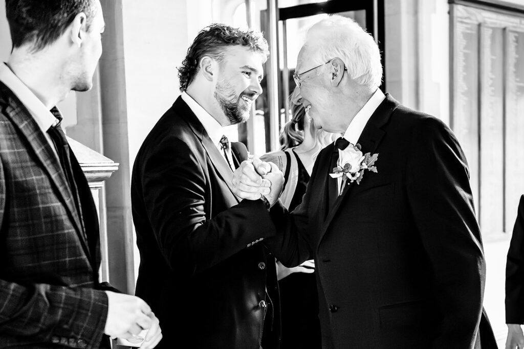 Groom hugging a guest, black and white, at Winchester Register Office, Hampshire
