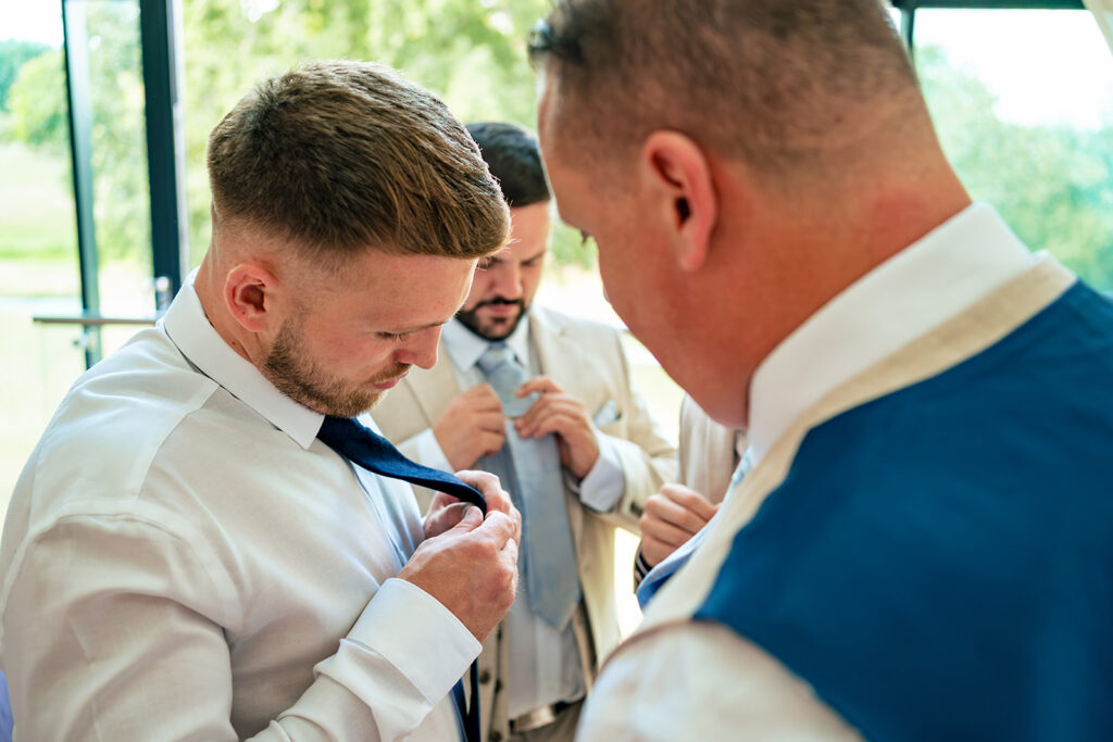 Groomsmen helping each other get ready at Old Thorns Hotel and Resort, Liphook