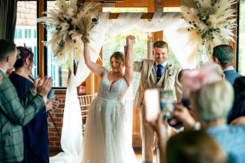 Newlyweds celebrating with arms in the air at Old Thorns Hotel and Resort, Liphook