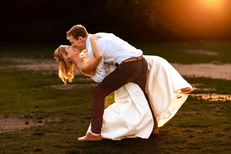 Groom carrying the bride at sunset at Great Ballard School, Eartham
